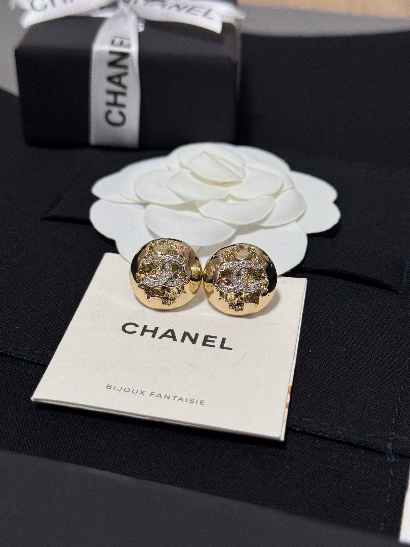 Gold-tone round stud earrings with crystal halo motif on a jewelry card