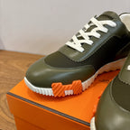 Olive green sneaker close-up with white laces and thick ridged white-and-orange sole