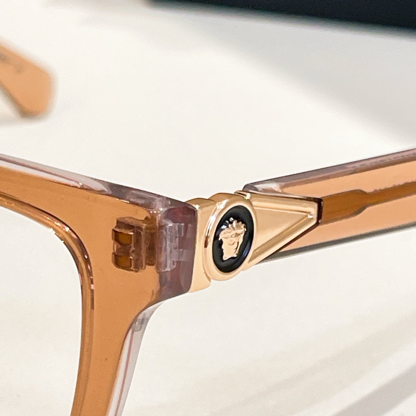 Versace eyeglasses close-up of gold hinge and clear temple arm.