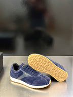 Prada unisex suede sneakers in blue with treaded rubber outsole visible under the shoe.