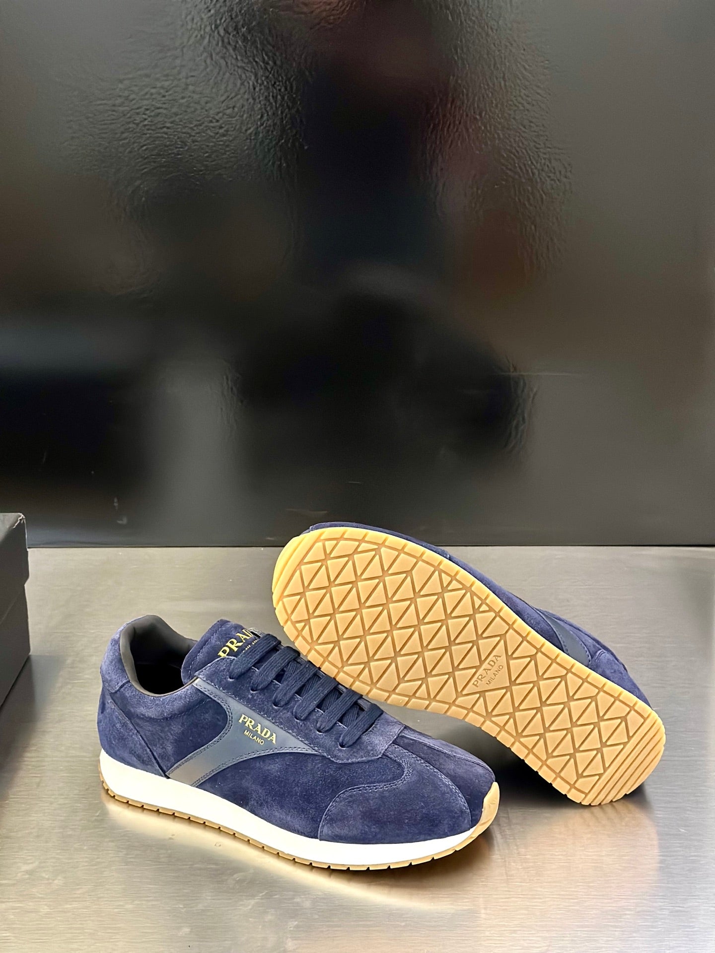 Prada unisex suede sneakers in blue with treaded rubber outsole visible under the shoe.