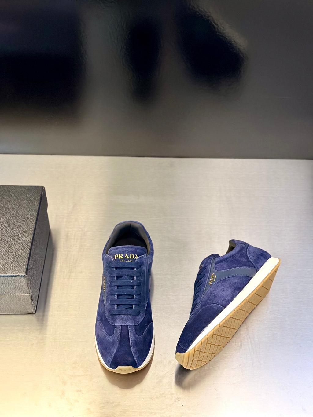 Prada unisex suede sneakers, blue, one shoe side view with lace-ups and cream sole edge.