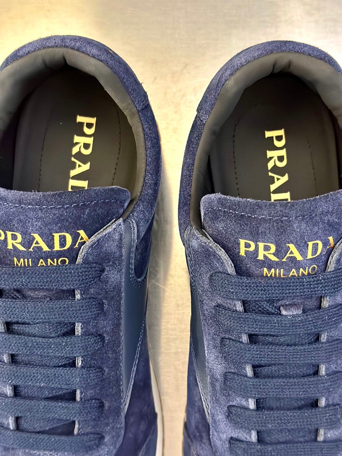 Prada unisex sneakers close-up of blue laces with “PRADA MILANO” text on inner tongue.