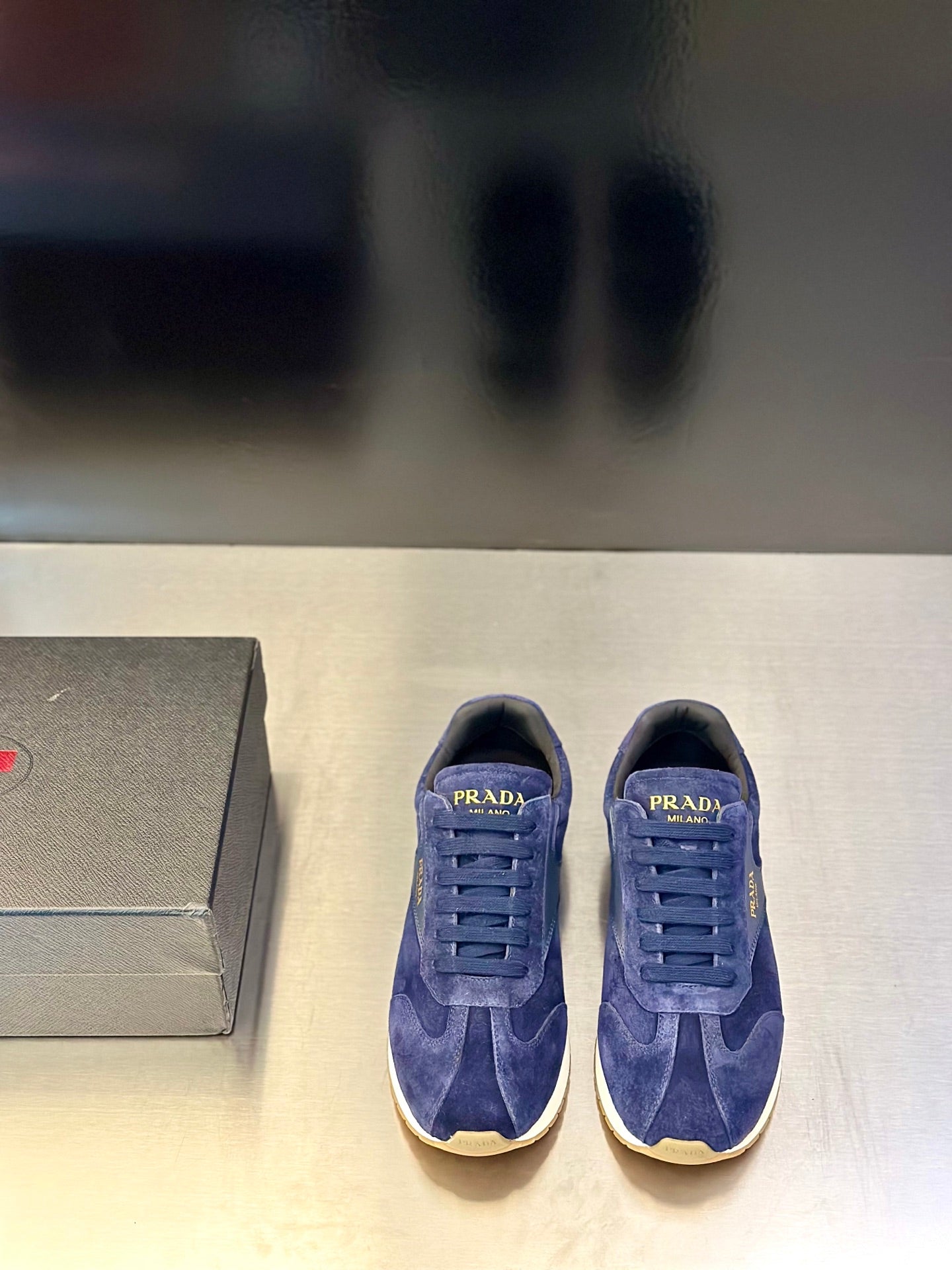 Prada unisex suede sneakers in blue, lace-up style with gold “PRADA” branding on tongue.