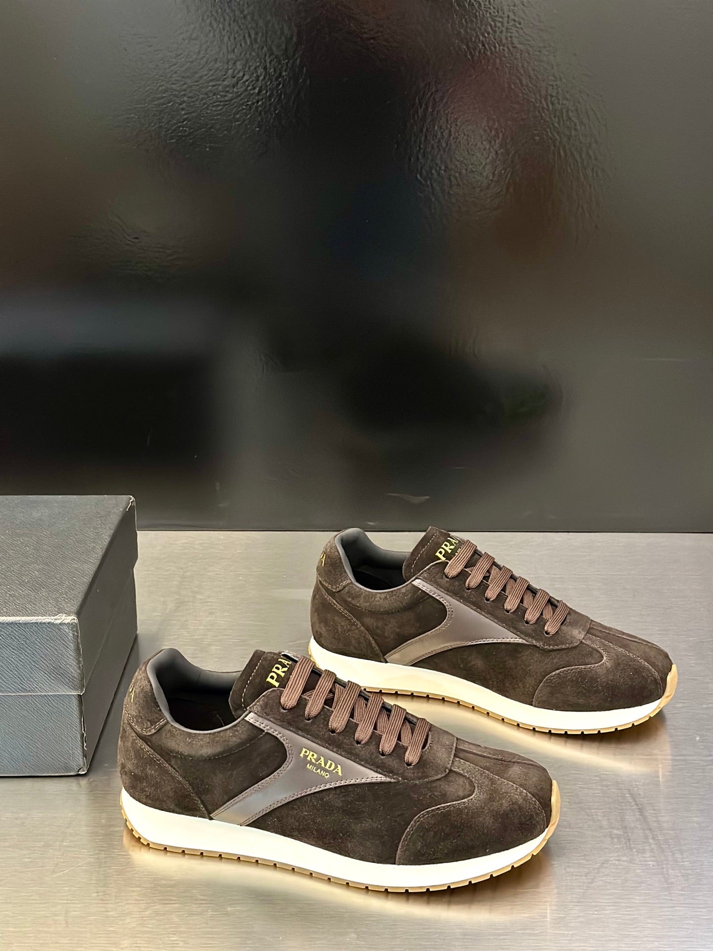 Prada unisex sneakers pair view in dark brown suede with off-white sole and laces.