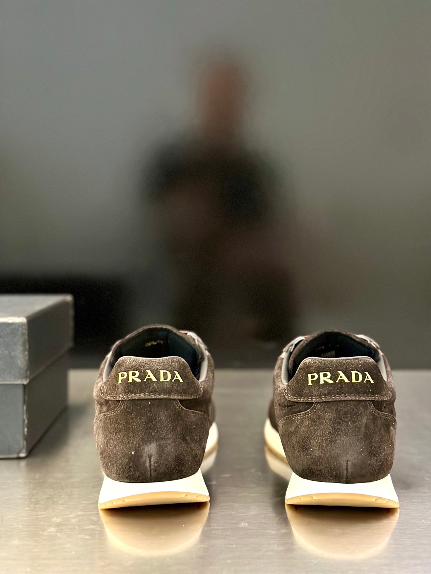 Prada unisex sneakers heel view with PRADA label and off-white sole tabs.