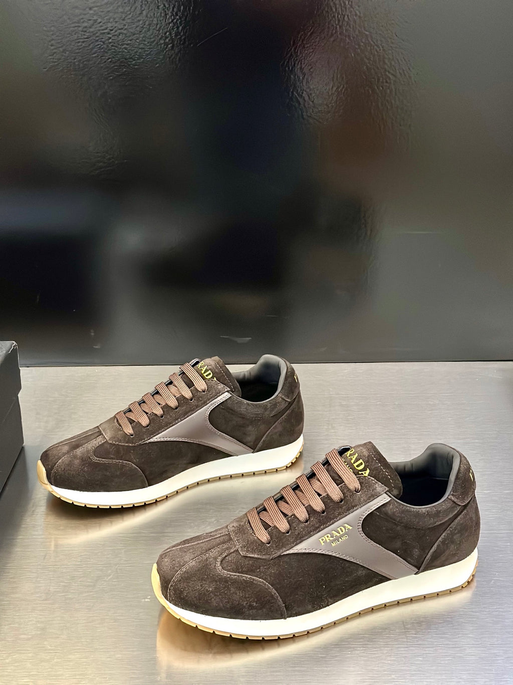 Prada unisex low-top sneakers, dark brown suede with white midsole and lace-up.