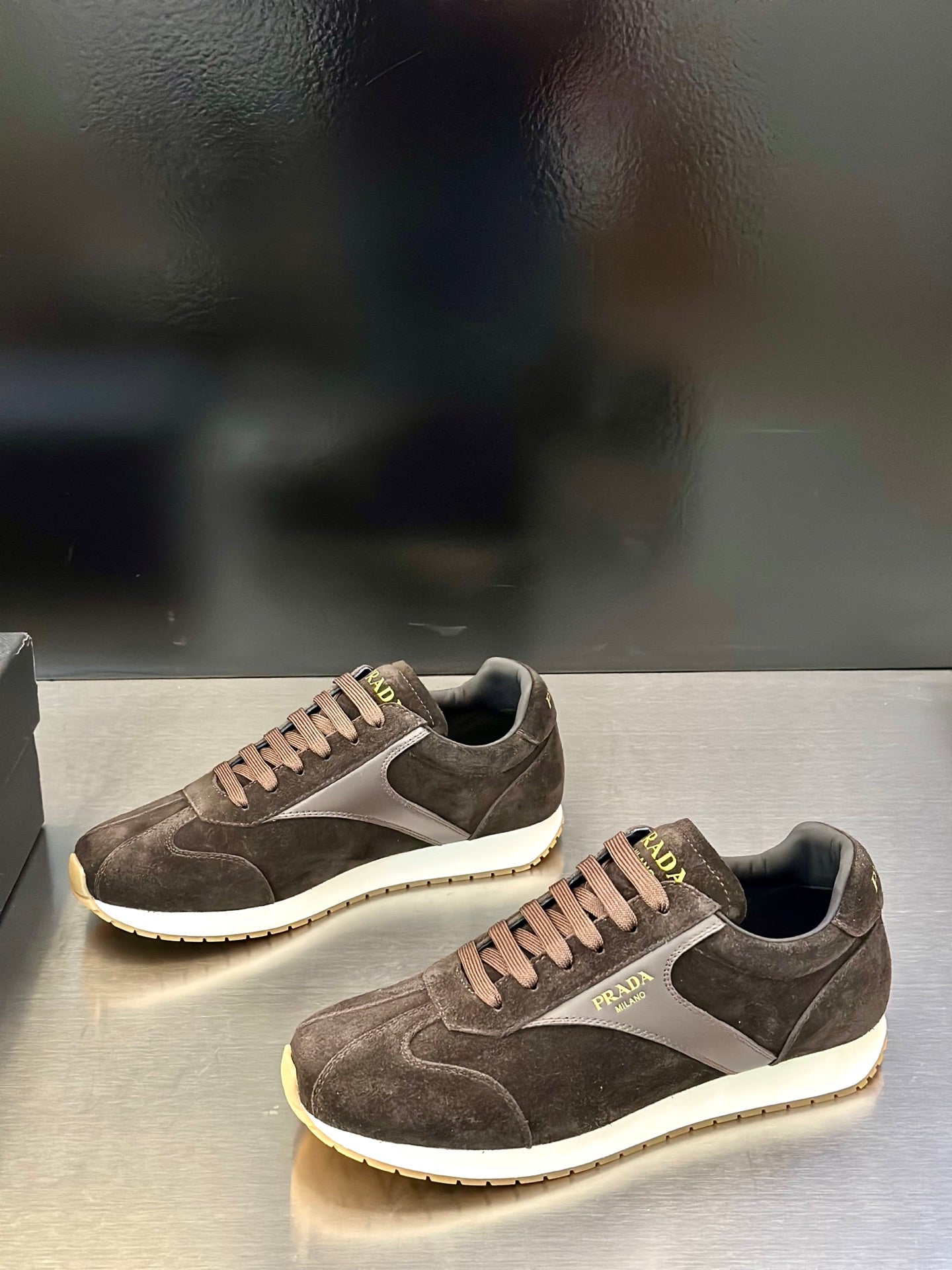 Prada unisex low-top sneakers, dark brown suede with white midsole and lace-up.