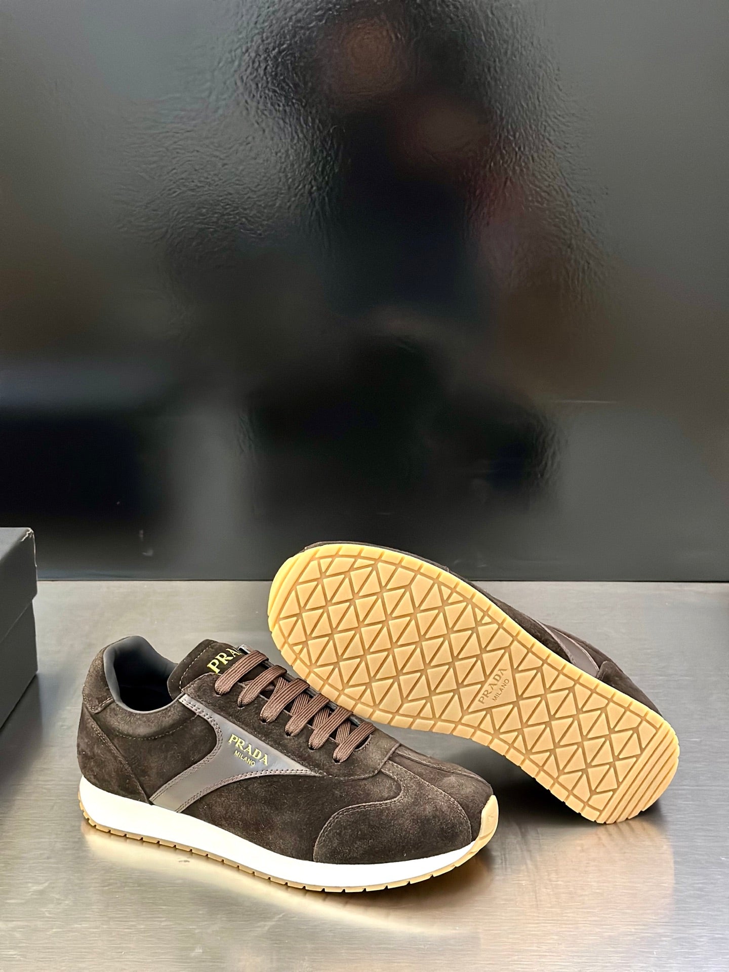 Prada unisex sneakers with visible outsoles; dark brown suede and tan tread soles.