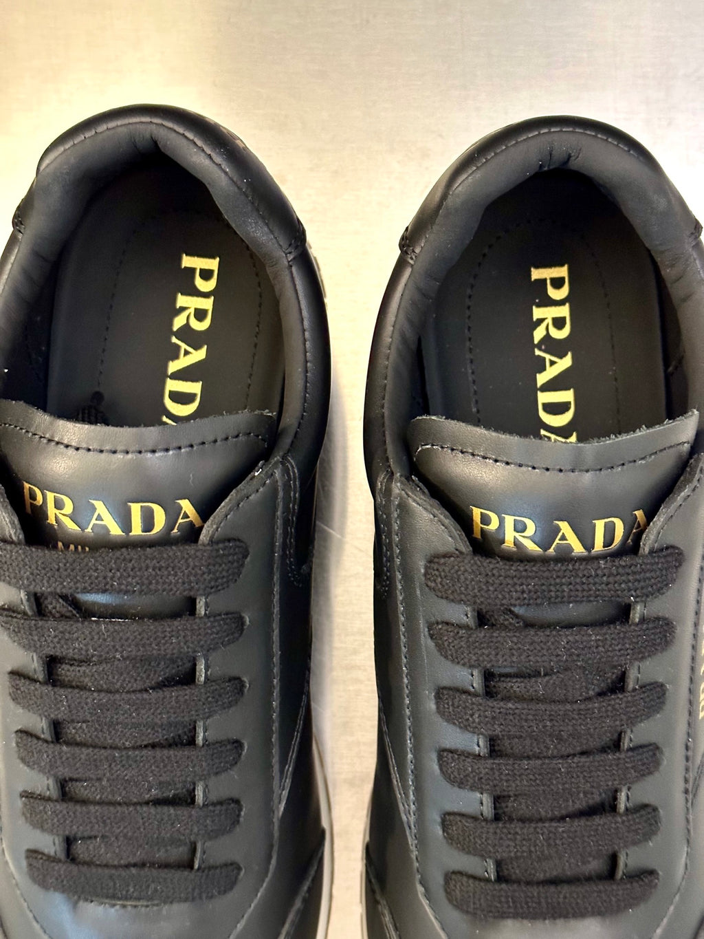 Prada logo close-up on dark leather sneaker tongue and lace panel