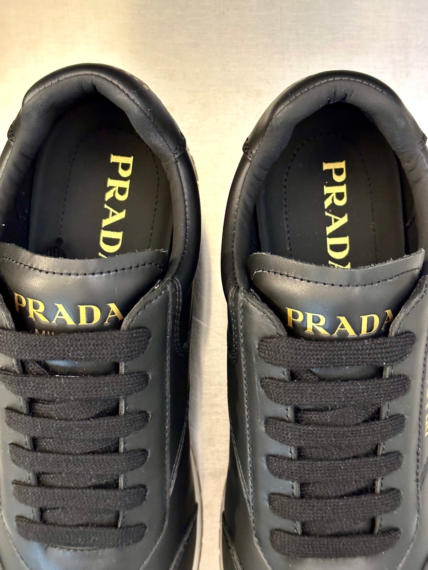 Prada logo close-up on dark leather sneaker tongue and lace panel