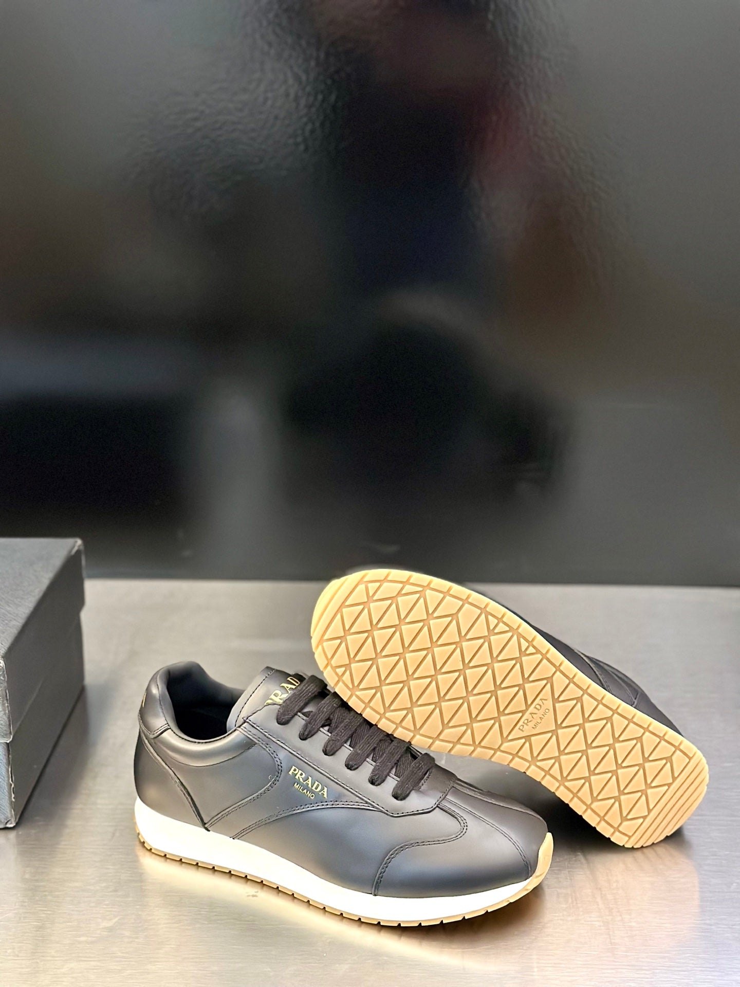 Prada leather lace-up sneaker with textured outsole visible, gray upper and light trim