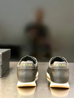 Prada leather sneaker pair in light gray, rear view with Prada logo on heel