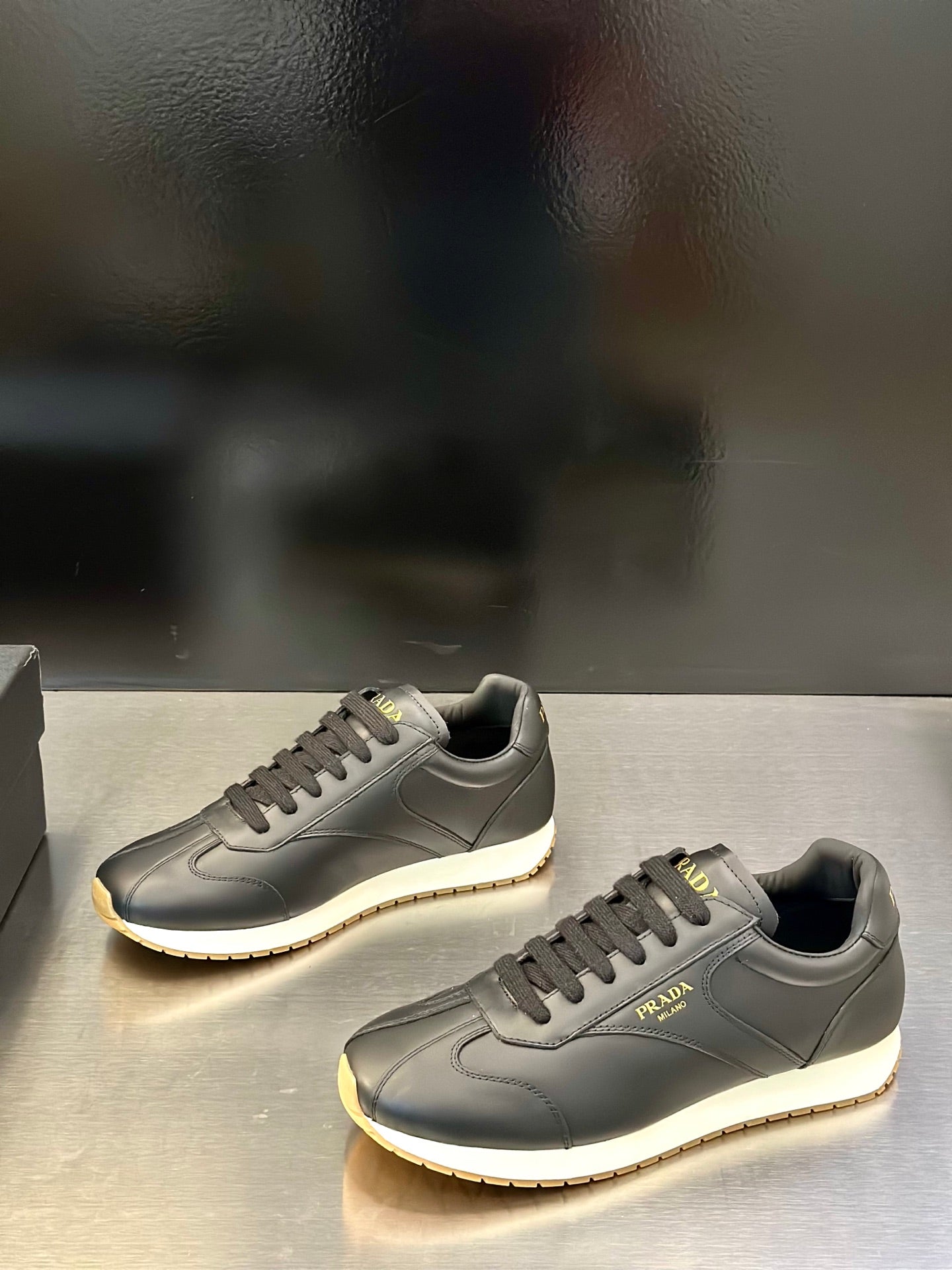 Prada leather lace-up sneaker in gray with lace-up front, side logo, and light sole