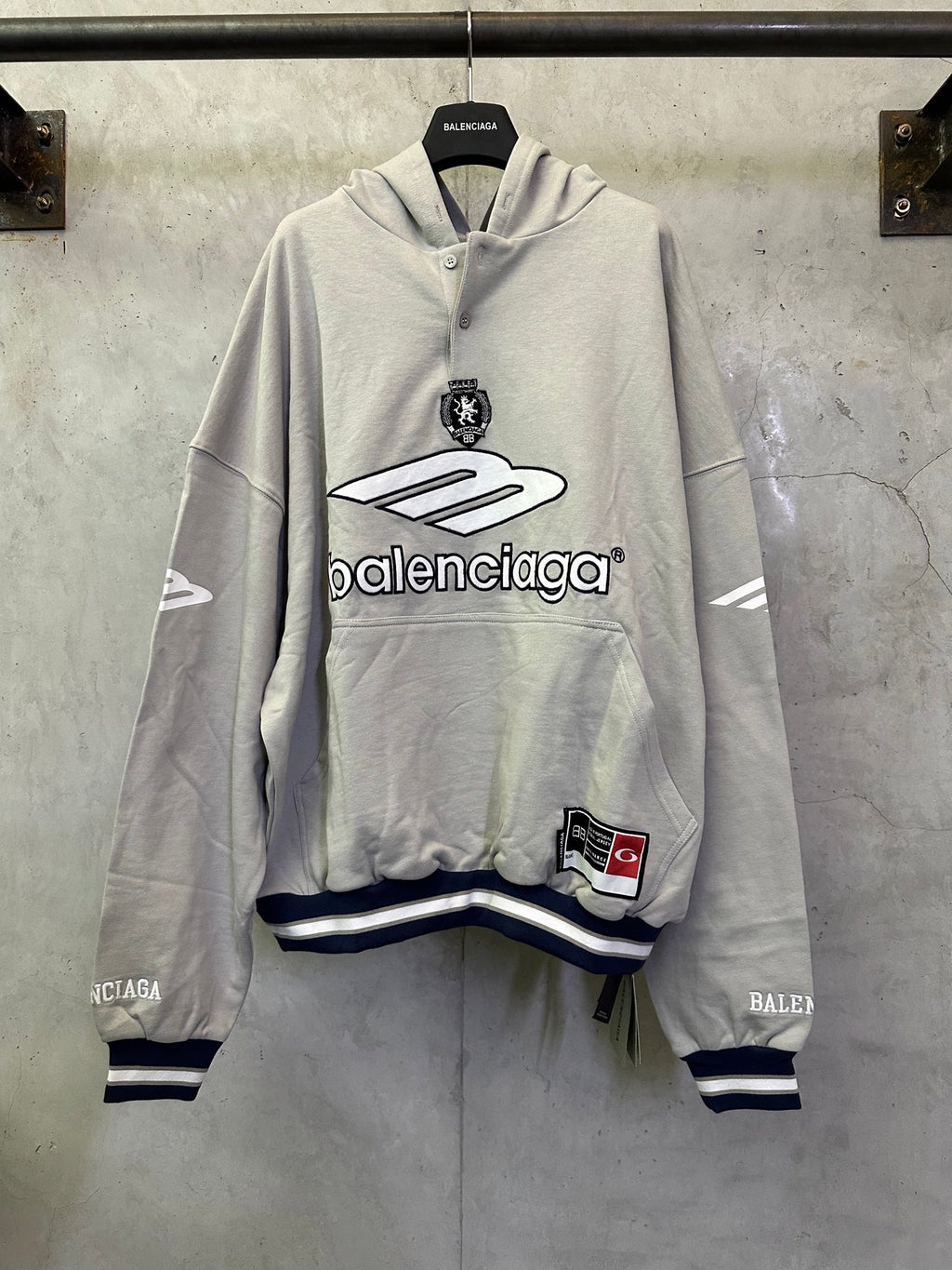 Light gray long-sleeve hoodie with front Balenciaga logo and striped cuffs at hem