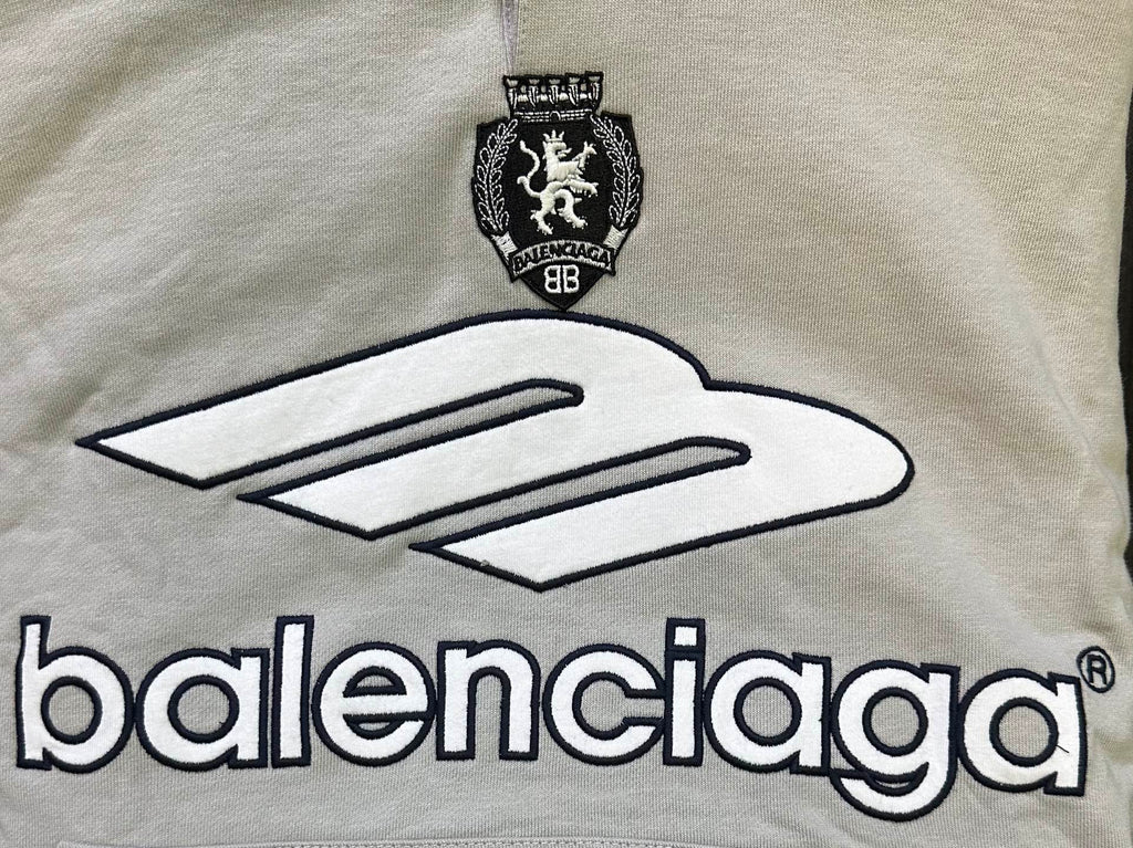 Light gray chest area of hoodie with large Balenciaga logo and crest emblem
