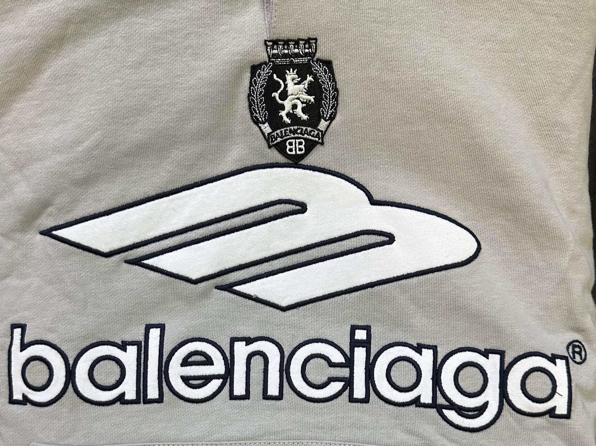 Light gray chest area of hoodie with large Balenciaga logo and crest emblem