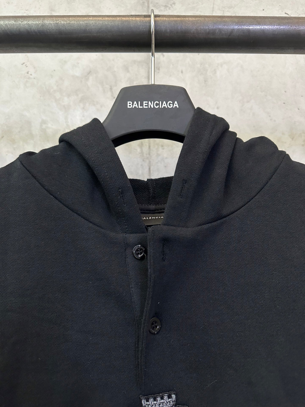 Black Balenciaga hoodie front close-up with button placket and crest emblem