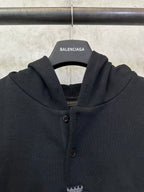 Black Balenciaga hoodie front close-up with button placket and crest emblem