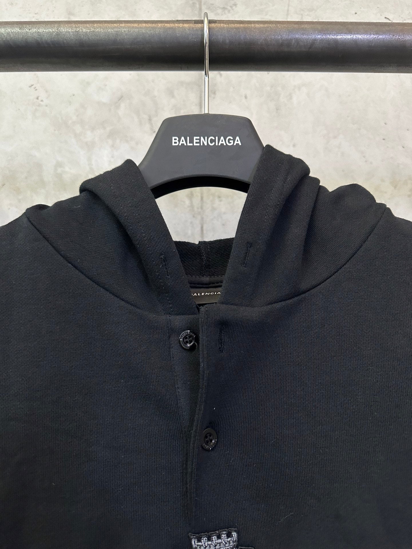 Black Balenciaga hoodie front close-up with button placket and crest emblem