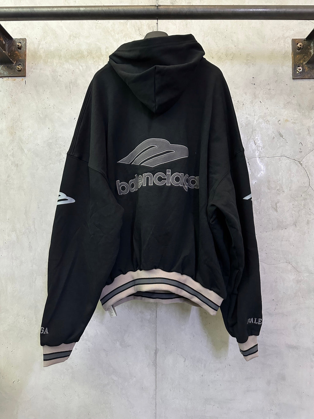 Black Balenciaga hoodie, back view with large logo print and striped hem cuffs