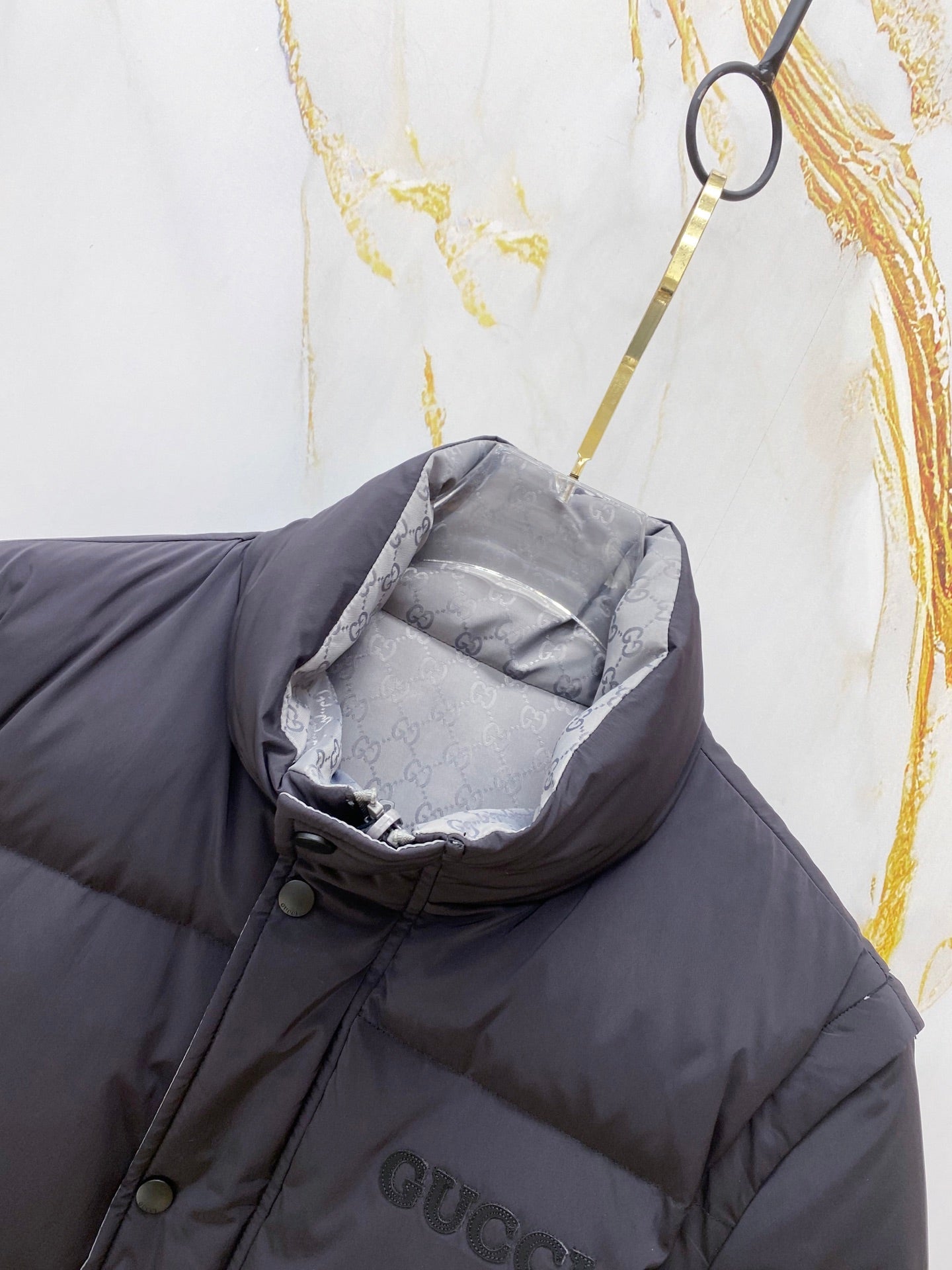 Dark gray puffer vest with hood pocket, buttons, and Gucci chest logo
