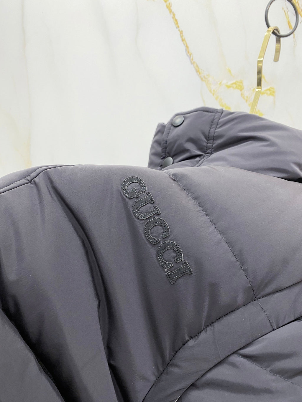 Dark gray puffer vest shoulder with embroidered Gucci logo