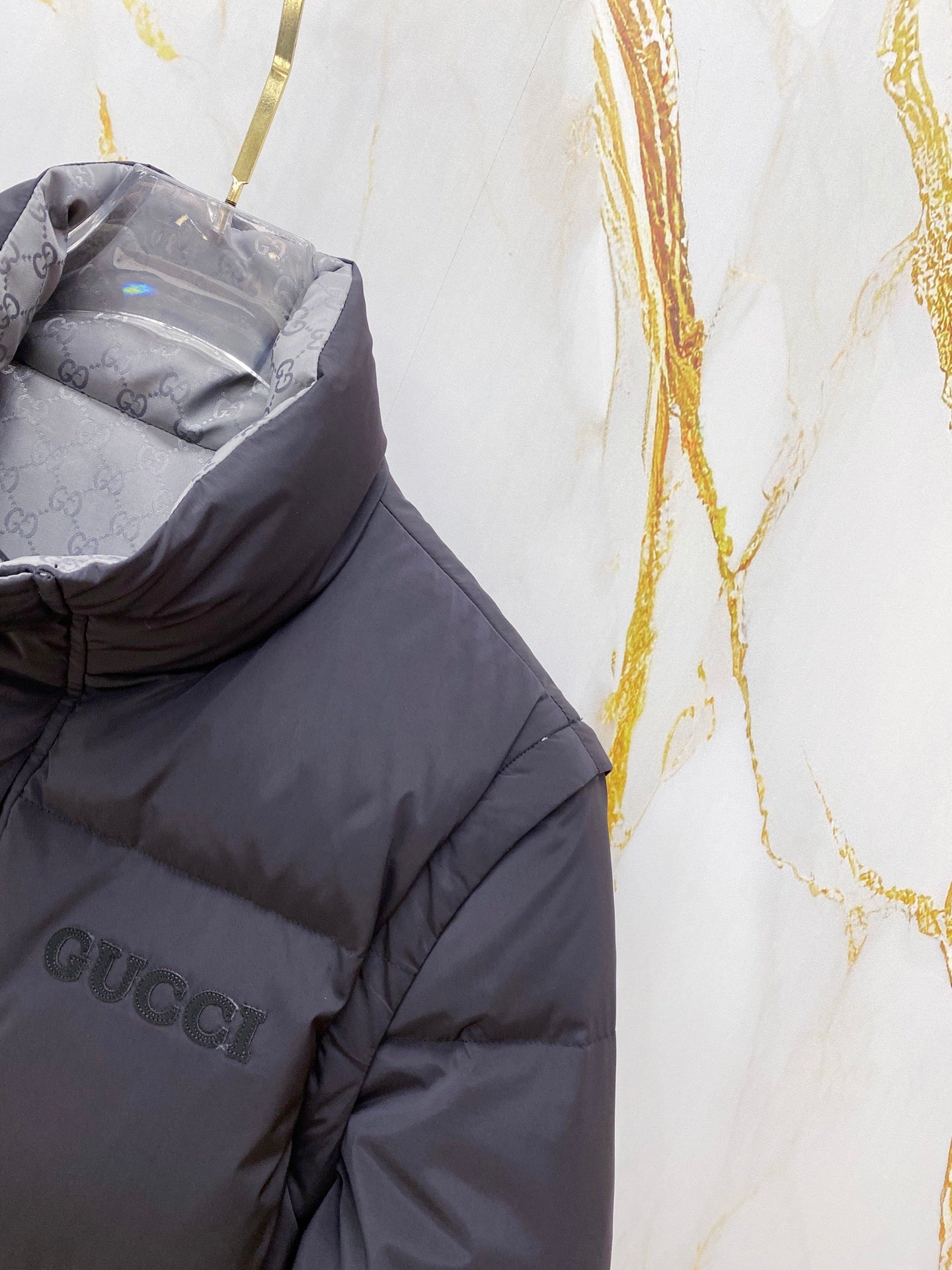 Dark gray puffer vest with Gucci logo patch on the chest