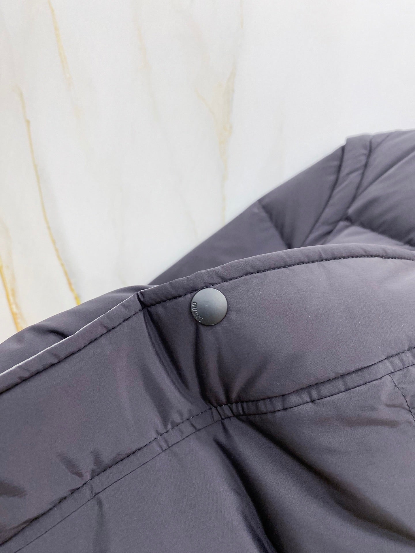 Dark gray puffer vest collar with snap button and stitched placket
