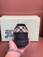 Dark leather sneaker held by hand, patterned interior collar and laced front