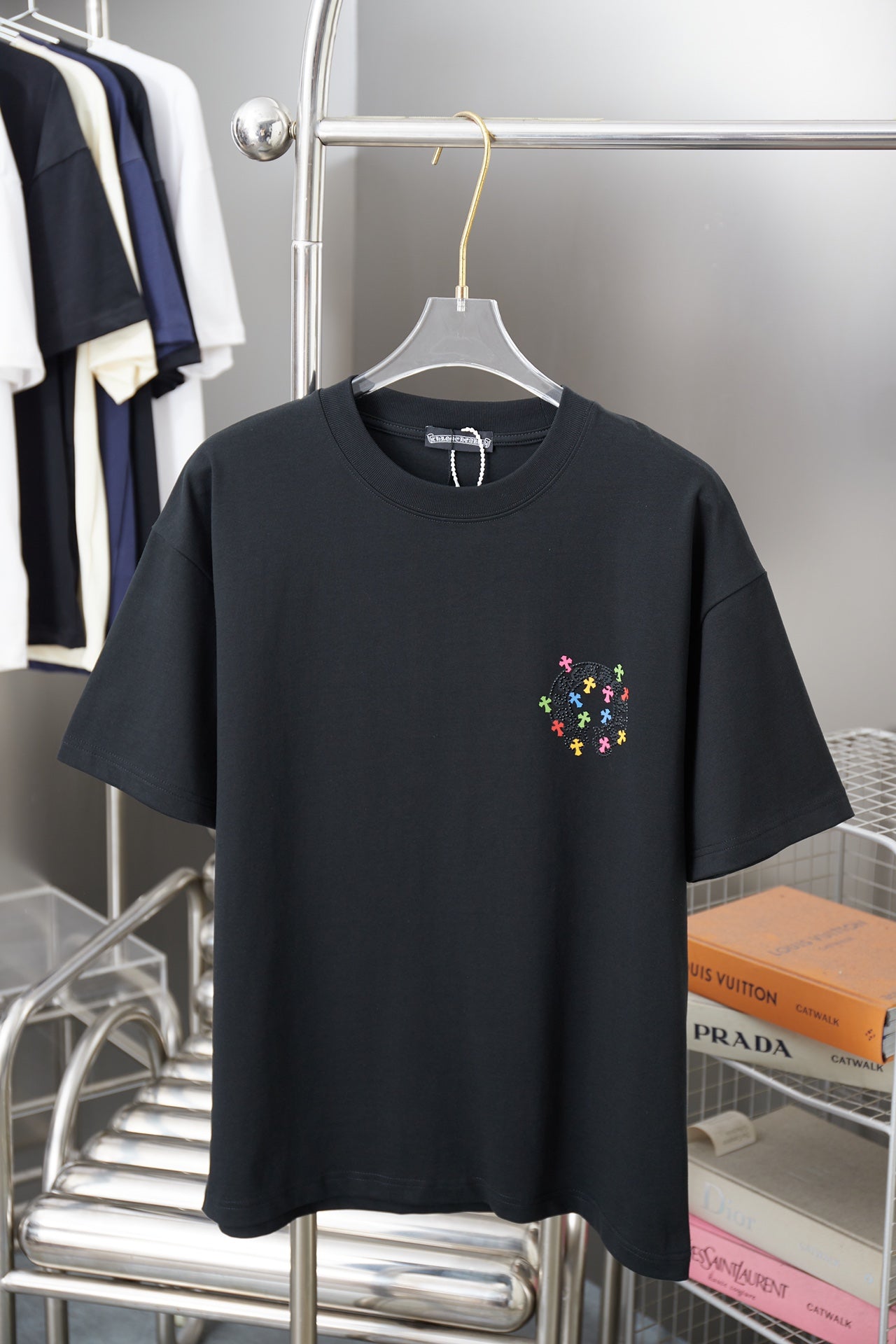 Black short-sleeve T-shirt with small multicolor cross-style graphic on chest