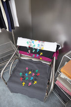 Folded gray T-shirts with multicolor cross prints on display