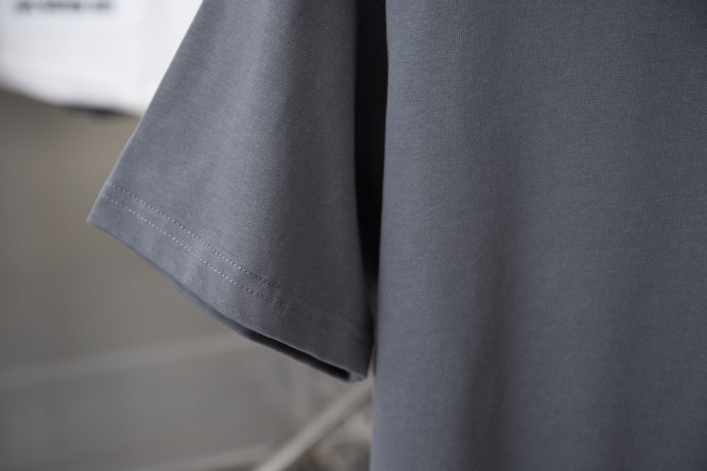 Gray T-shirt sleeve and hem with visible stitching detail