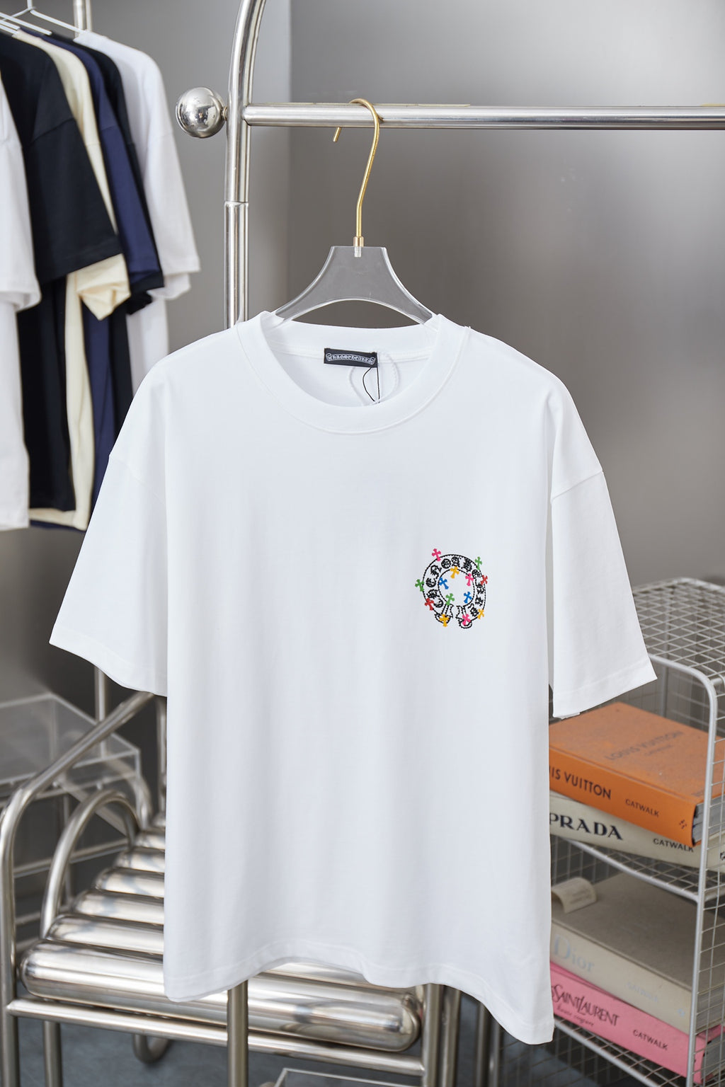 White graphic T-shirt with small circular multicolor cross logo at left chest