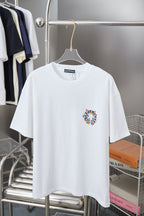White graphic T-shirt with small circular multicolor cross logo at left chest