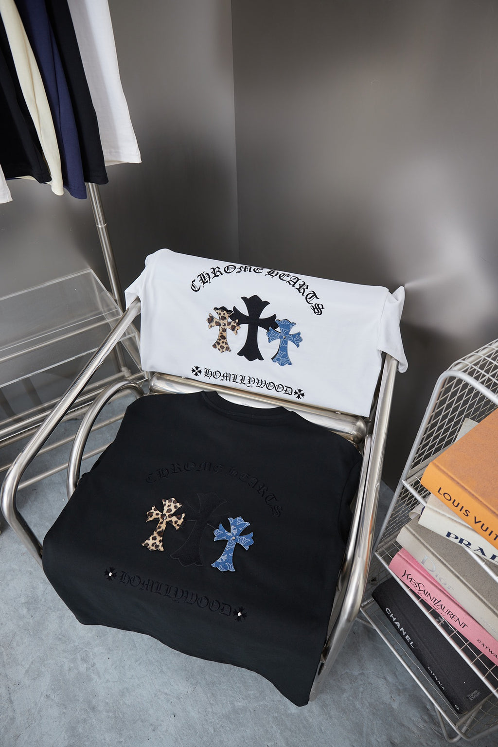 Two folded black and white graphic T-shirts with cross embroidery on rack