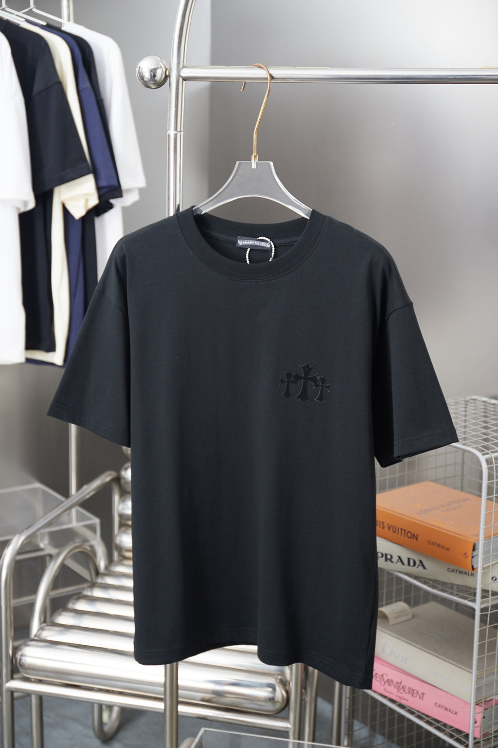 Black crew-neck T-shirt with short sleeves and small dark embroidered graphic on chest