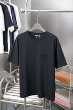 Black crew-neck T-shirt with short sleeves and small dark embroidered graphic on chest