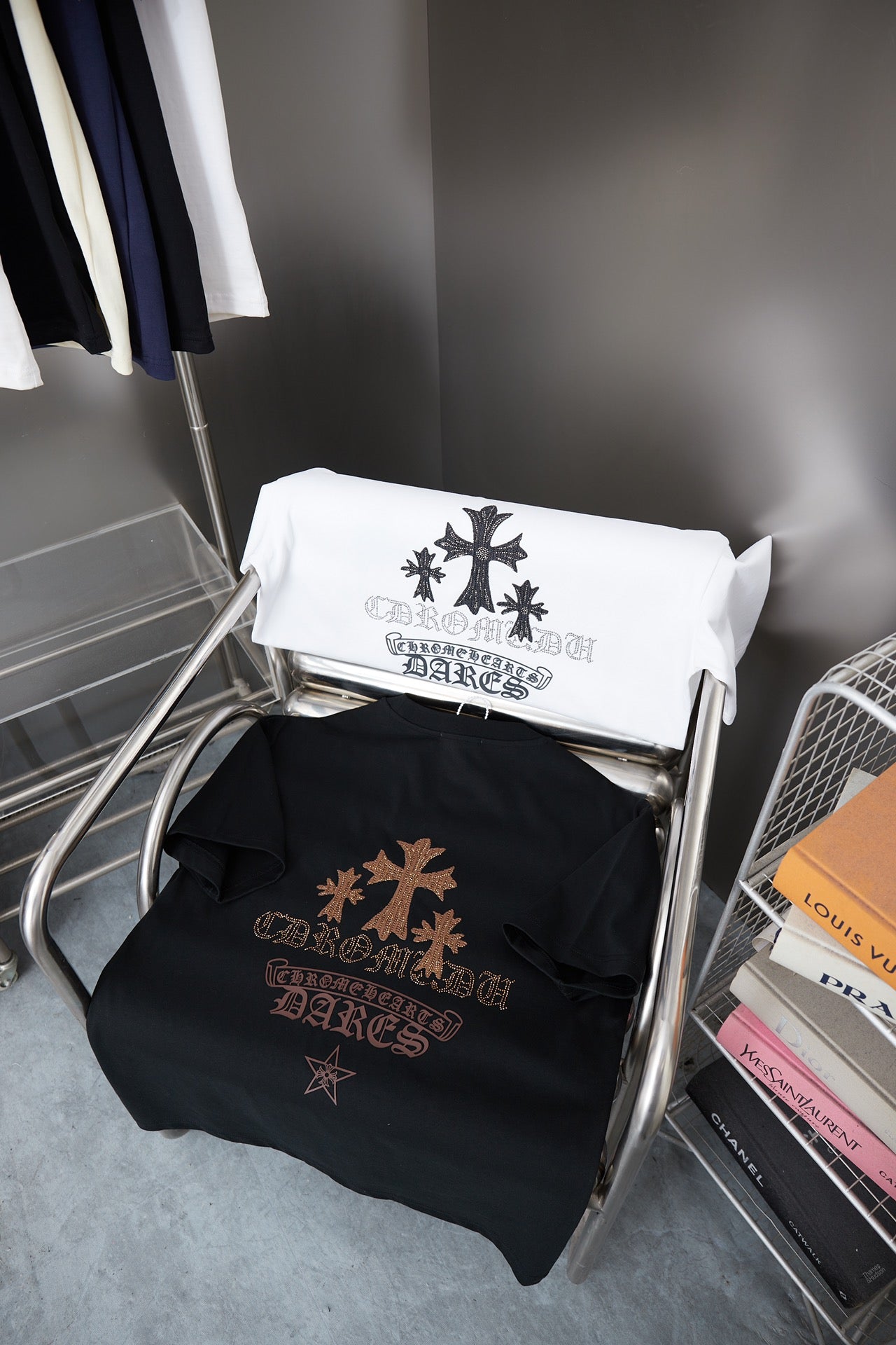 Folded graphic T-shirts on a metal rack, showing dark and white shirts