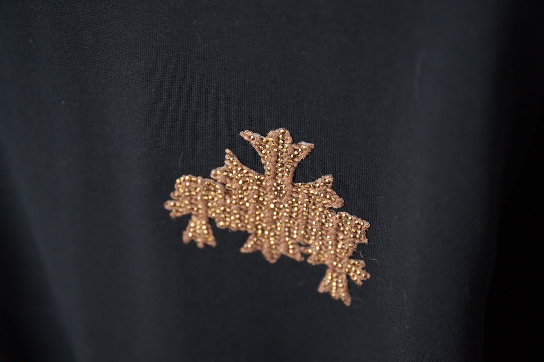 Embroidered rhinestone leaf and star emblem on a dark T-shirt
