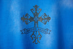 Blue T-shirt with dark rhinestone-style cross and banner emblem detail
