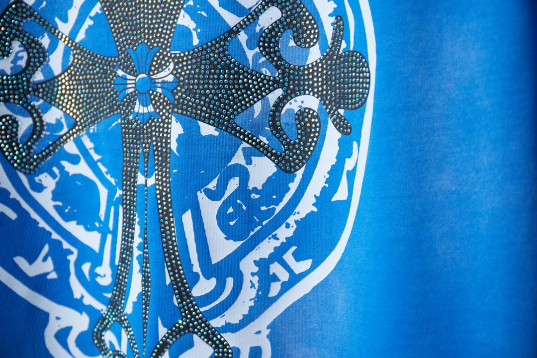 Blue T-shirt with rhinestone-style crest graphic and ornate floral details