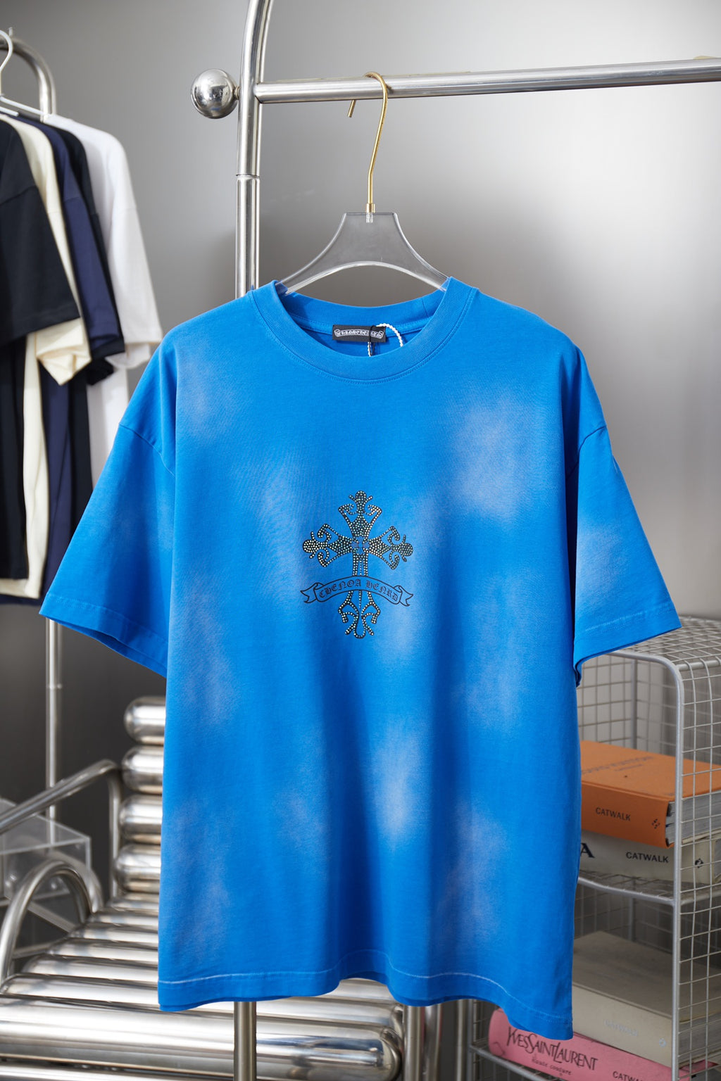 Blue short-sleeve T-shirt with small dark cross graphic on the chest