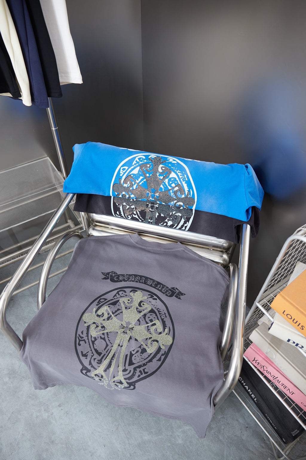 Stack of folded short-sleeve graphic T-shirts in gray and blue with crest designs