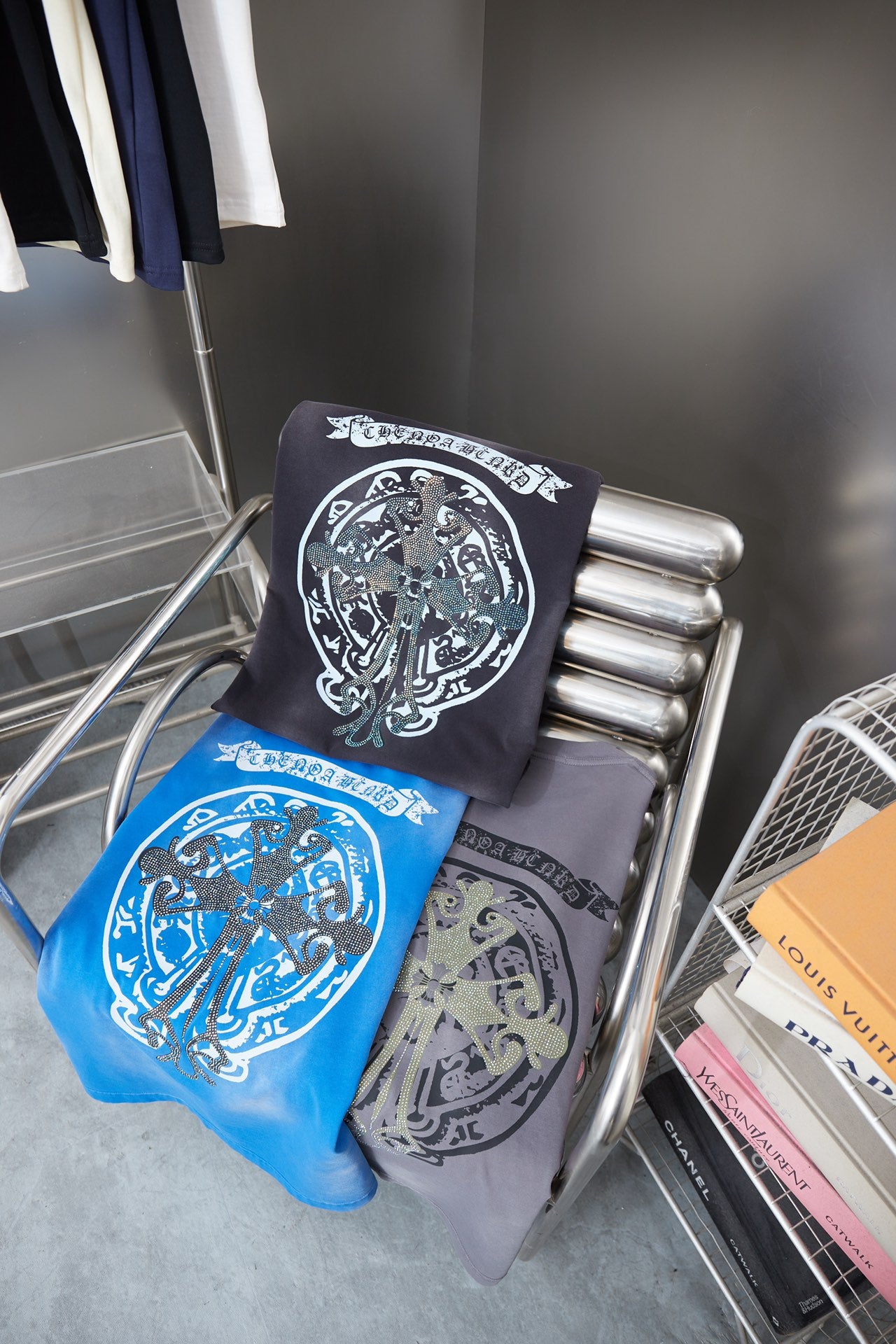 Stack of folded short-sleeve graphic T-shirts in black, blue, and gray with crest designs