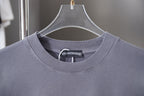 Dusty blue crewneck T-shirt neckline with ribbed collar and brand tag at center