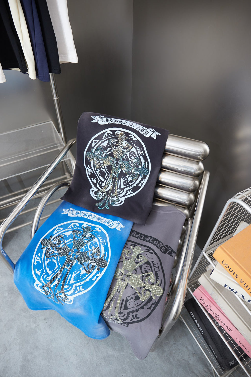 Folded dark navy and blue graphic T-shirts on metal display stand