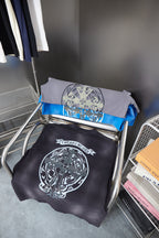 Folded dark navy and blue graphic T-shirts stacked on a metal stand