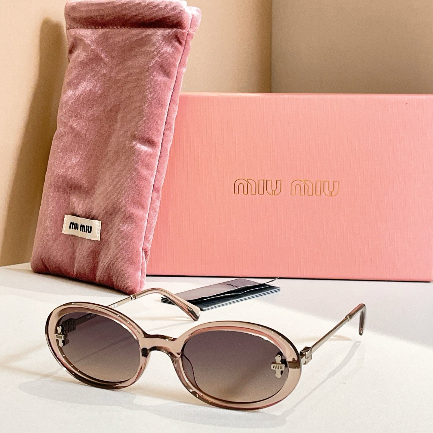 MiuMiu round sunglasses with champagne frames, gold accents, and dark lenses