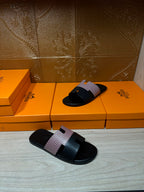 Hermes sandals with black slide sole and light patterned strap, one pair standing and one lying